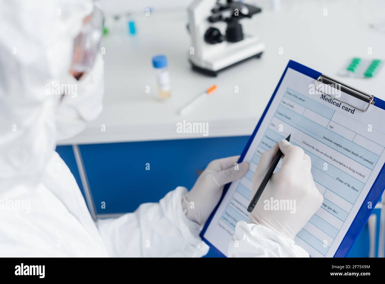 Medizinische Karte und Stift in den Händen des Wissenschaftlers in Schutz Uniform auf verschwommenem Vordergrund Stockfoto