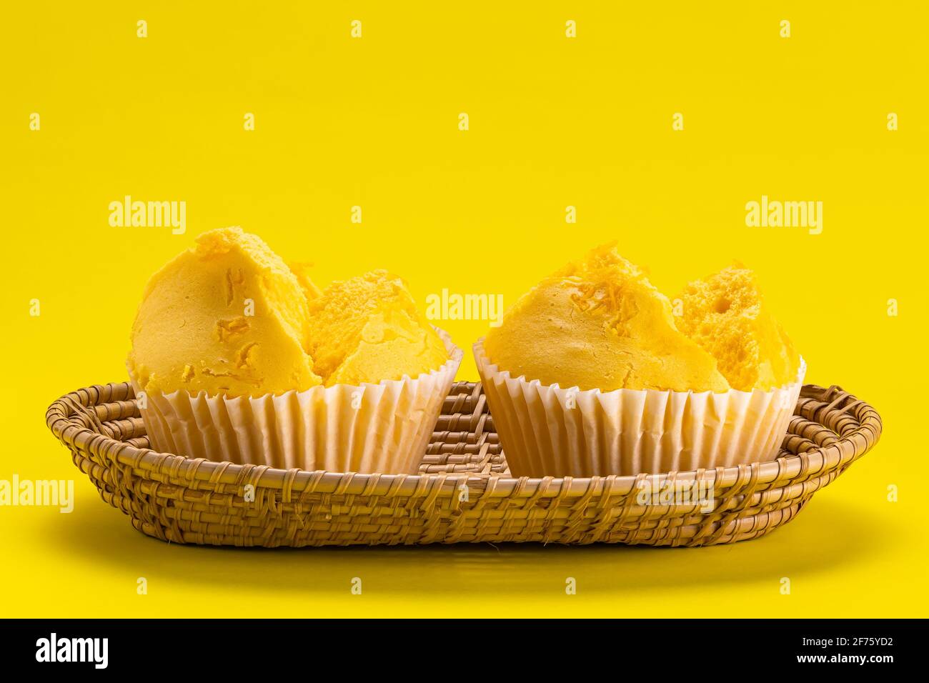 Gelbe Kollektion. Seitenansicht von Eigelb-Fäden gelben Zuckerkuchen aus Baumwolle in Bambusablage auf gelbem Hintergrund. Stockfoto