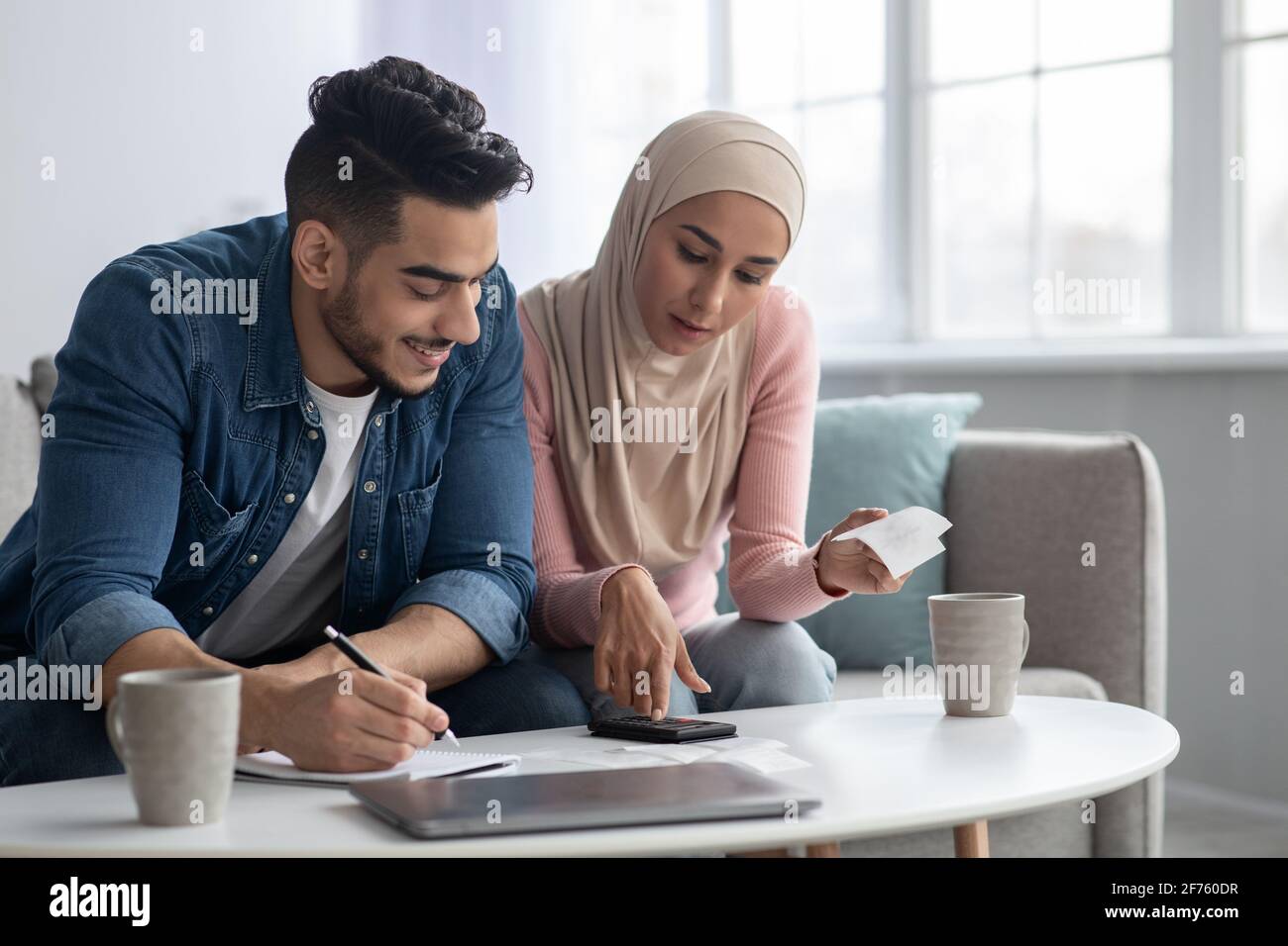 Positive muslimische Familie, die ihre Verauslagungen zählt, sich wohlhabend fühlt Stockfoto