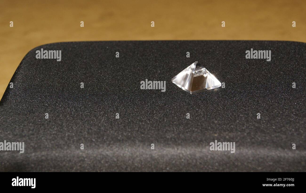 Pyramide. Kristallpyramide auf schwarzem Hintergrund basierend auf Travertin-Marmor in der Seitenansicht und selektiver Fokus im Zoom im Kopierbereich Stockfoto