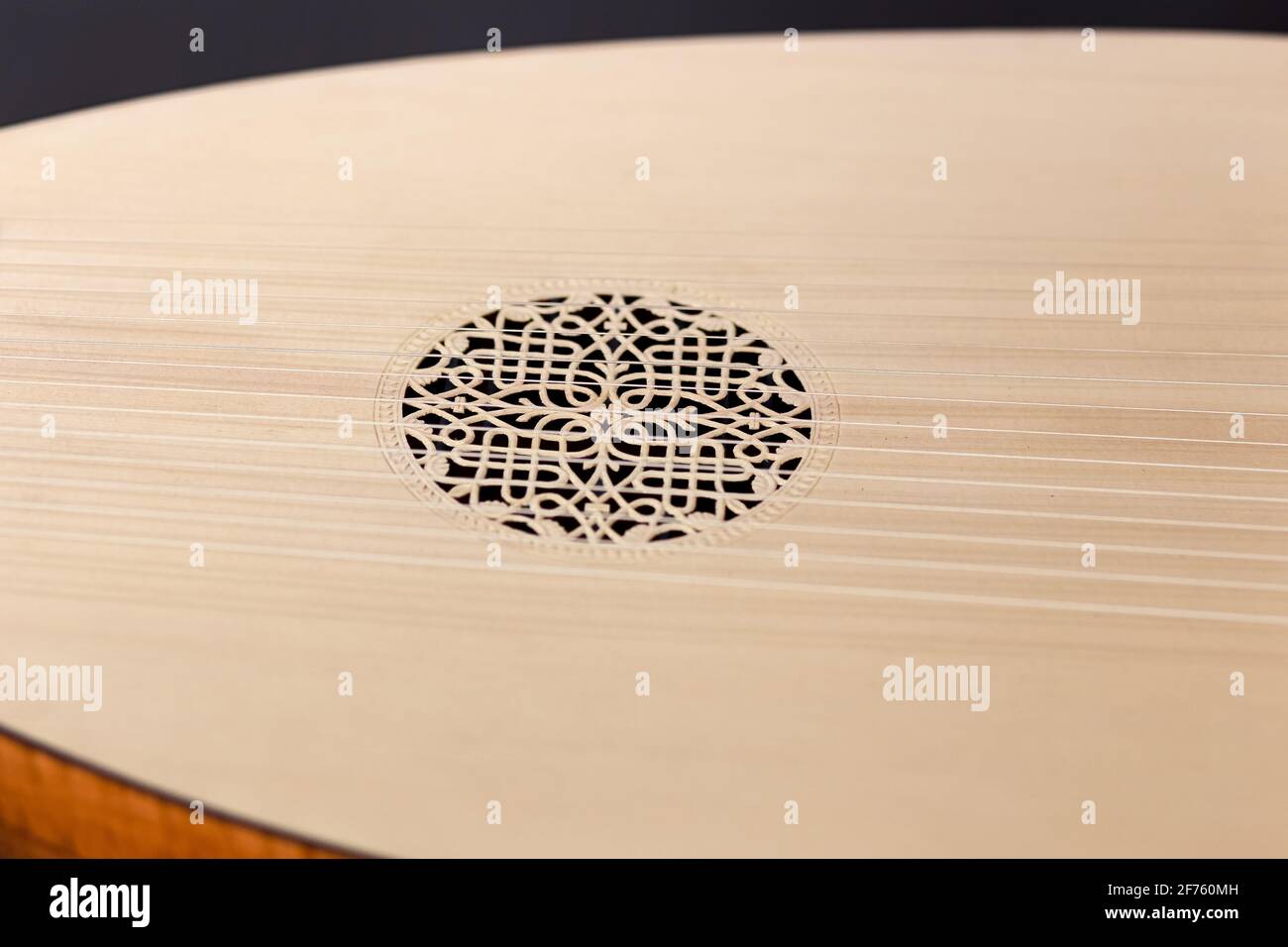 Nahaufnahme des Soundboards mit dem geschnitzten Resonator des Lauteninstruments. In der Mitte befindet sich ein schönes Muster in einem Kreis. Gestreckte Saiten entlang des gesamten Stücks. Stockfoto