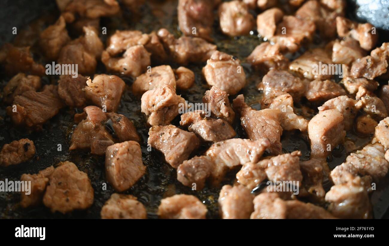 Fleischstücke werden in einer Pfanne gebraten. Wohnküche. Nahaufnahme. Hochwertige 4k-Aufnahmen Stockfoto