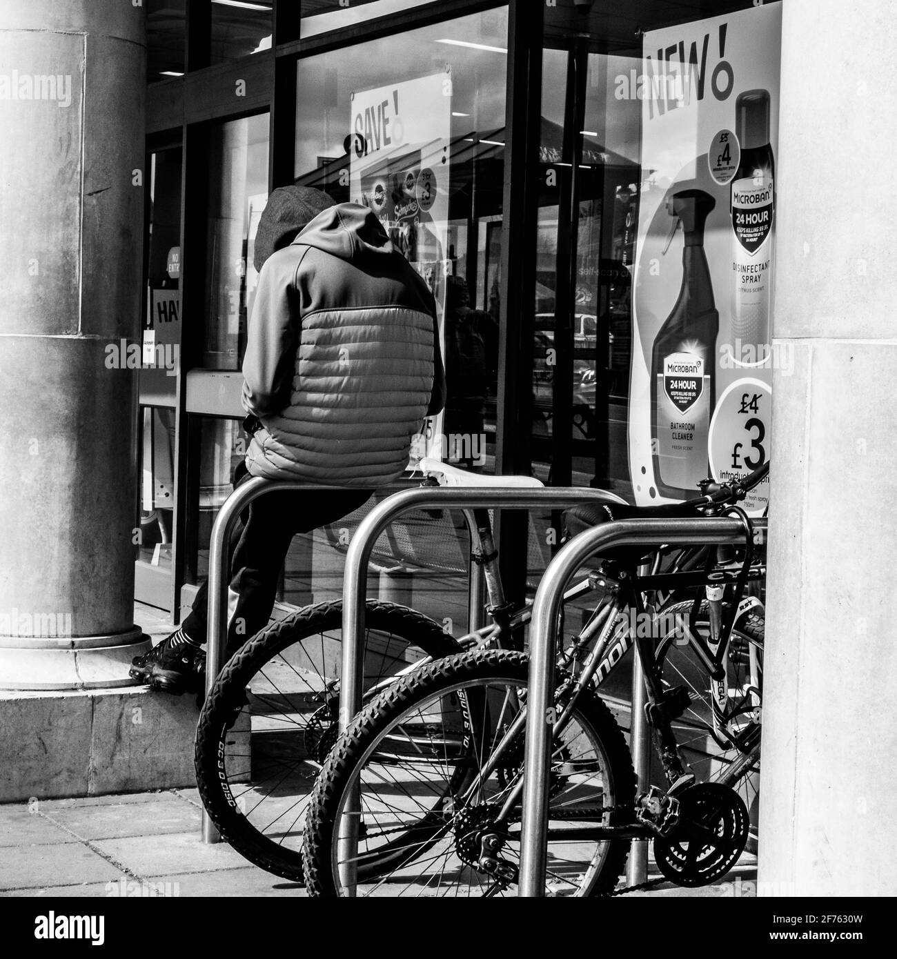 Epsom Surrey, London, Großbritannien, April 5 2021, junger Mann, der einen Hoodie trägt, allein auf EINEM Fahrradparkplatz sitzt Stockfoto