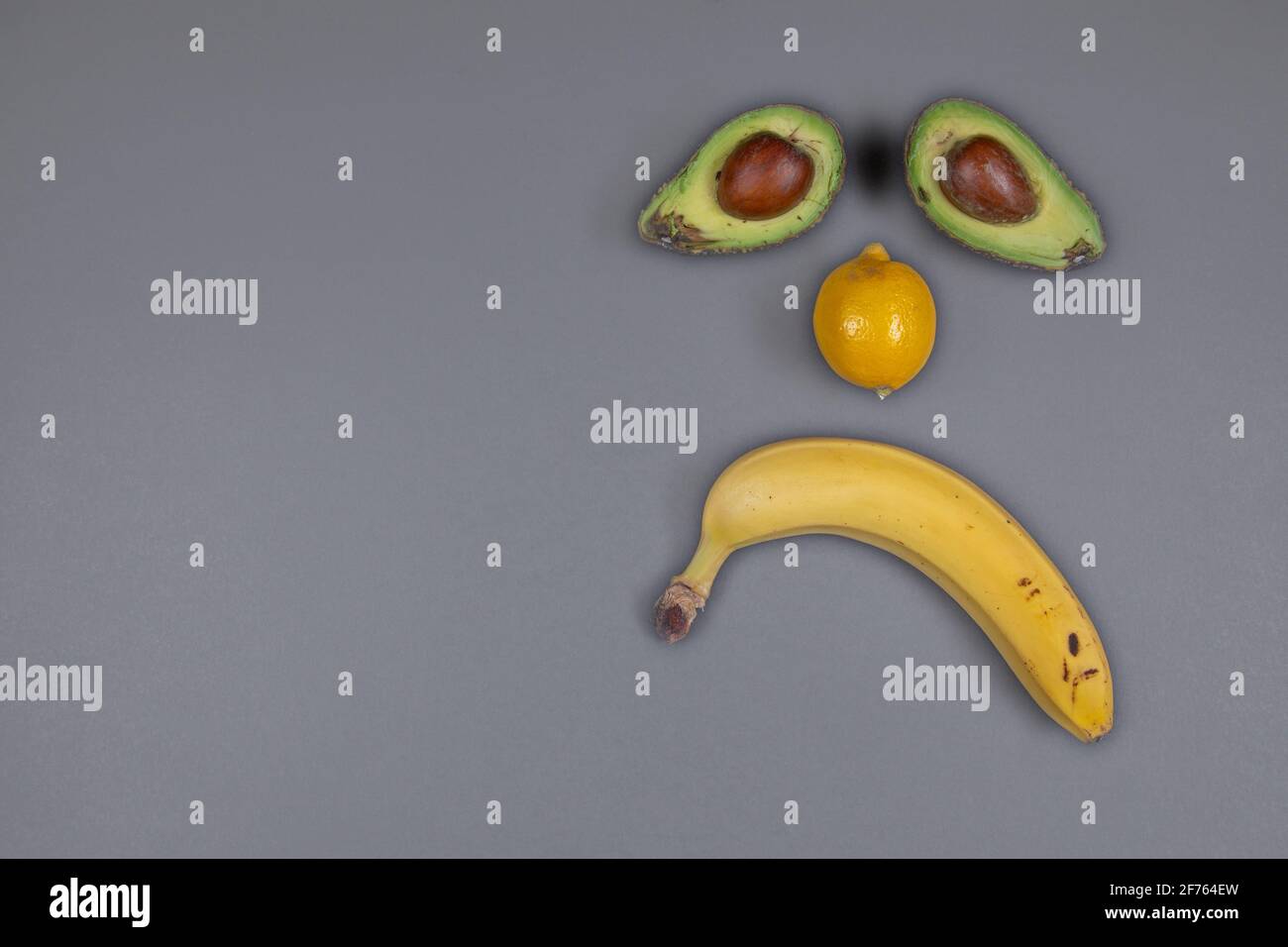 TRAURIGES GESICHT AUS BANANE, AVOCADO, ZITRONE Stockfoto
