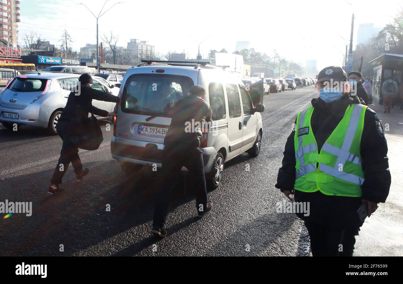 KIEW, UKRAINE - 05. APRIL 2021 - EIN Polizeibeamter, der an der Haltestelle für öffentliche Verkehrsmittel neben zwei Männern gesehen wird, die ein Auto schieben, Kiew, Hauptstadt der Ukraine.Quelle: Ukrinform/Alamy Live News Stockfoto