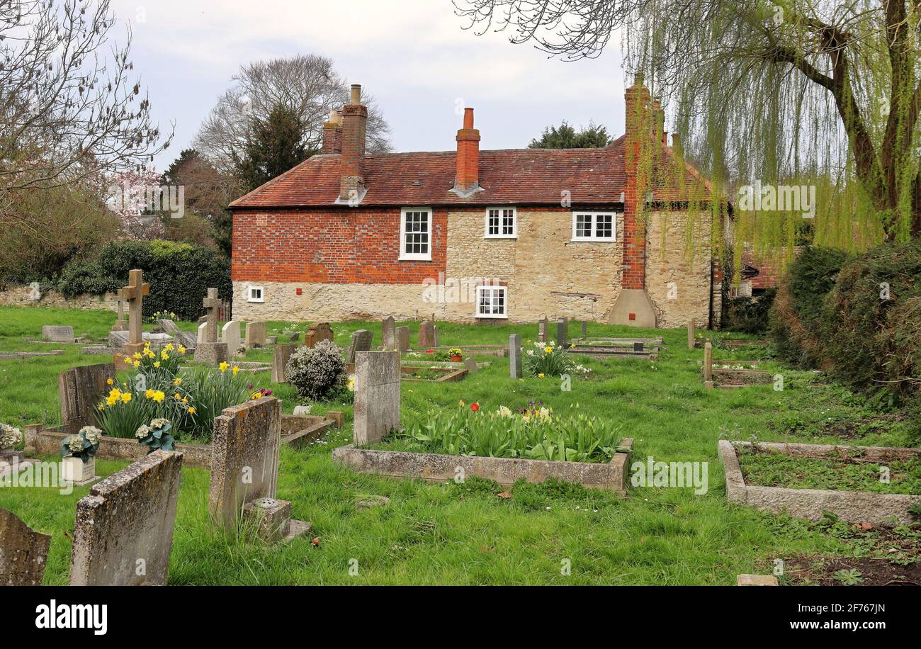 Rustikales englisches Landhaus bei einem Dorfkirche Friedhof mit Frühling Umherschlingern die Gräber Stockfoto