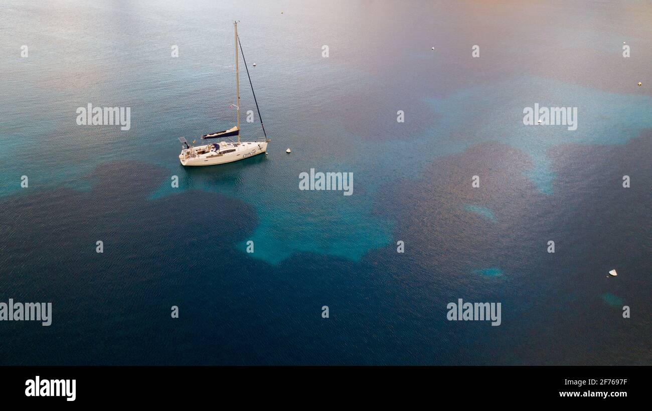 Luftdrohnenaufnahme eines Segelbootes, das in einer Bucht der Insel Cabrera im Archipel der Balearen, Spanien, verankert ist Stockfoto