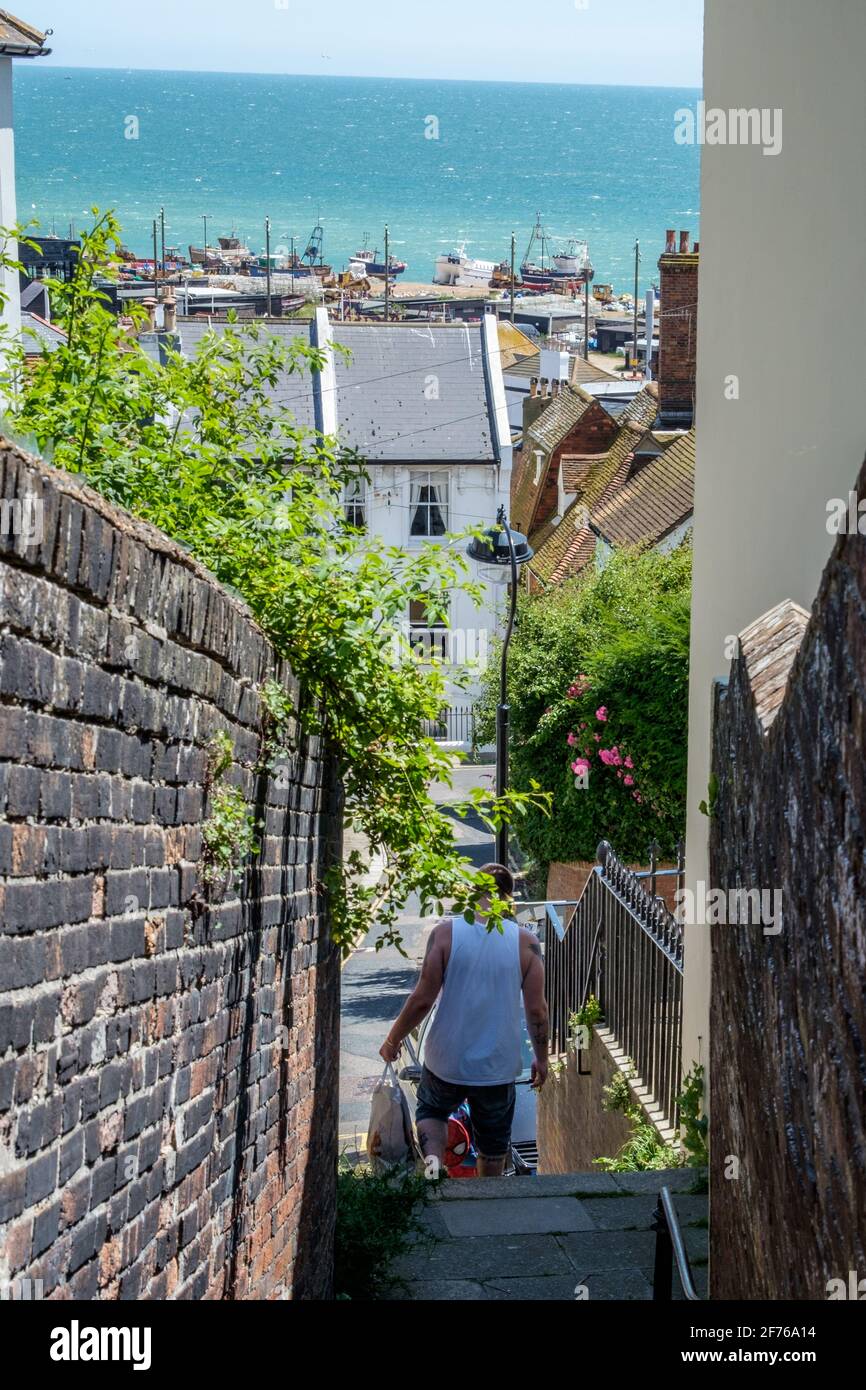 Staycation Idee. Ein Mann geht die Stufen hinunter, die vom West Hill zur Altstadt von Hastings führen. Slade Beach und der englische Kanal im Hintergrund Stockfoto