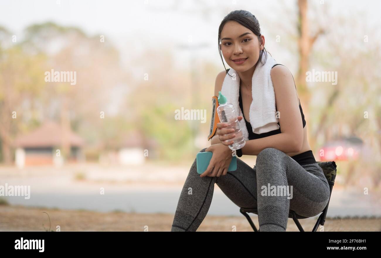 Junge athletische Frau hält Wasser aus einer Flasche nach dem Laufen Im Park Stockfoto