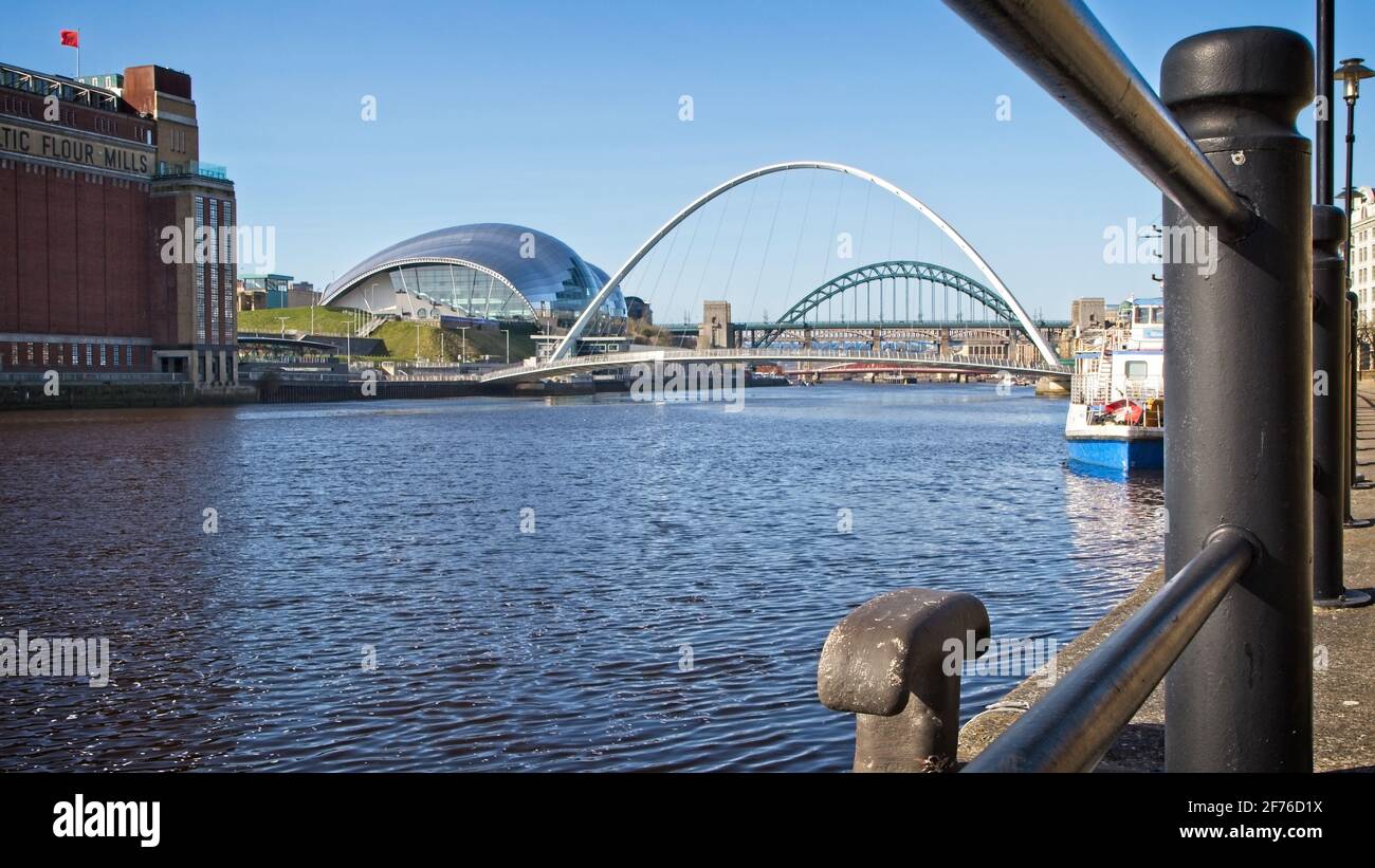 Blick durch die Quayside Geländer den Fluss Tyne hinauf in Richtung Millennium und Tyne Bridges and Sage Center in Newcastle-Gateshead, Tyne und Wear. Stockfoto