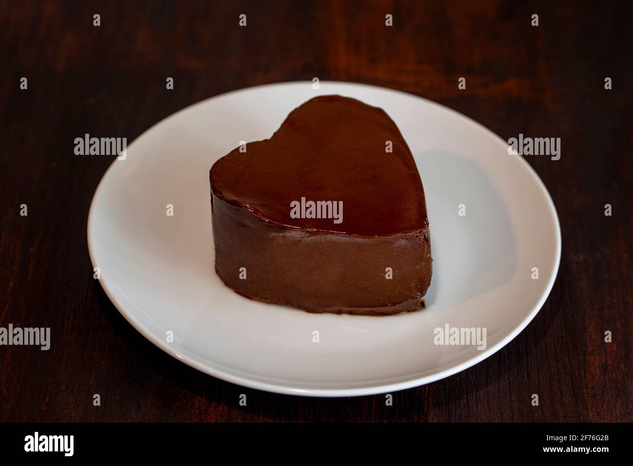 Herzförmige Schokoladenkuchen auf Teller auf dunklem Holzhintergrund Stockfoto