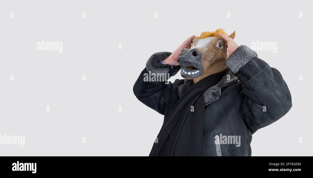 Mann in einer Pferdemaske. Selektiver Fokus. Pferd trägt einen Mantel. Männliches Gestüt. Banner, Kopierraum. Stockfoto