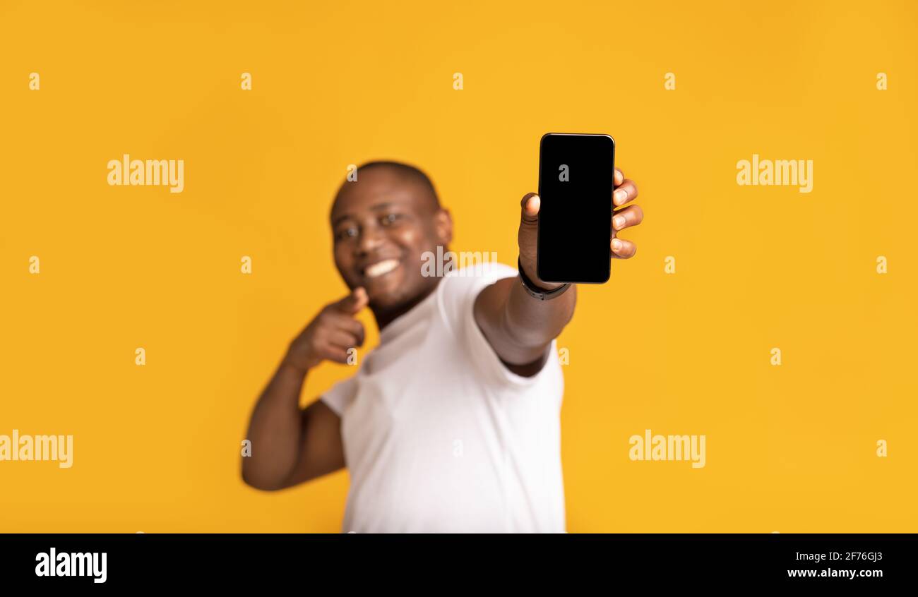 Fröhlicher afroamerikanischer Mann mittleren Alters in weißem T-Shirt Zeigt den Finger am Telefon an Stockfoto