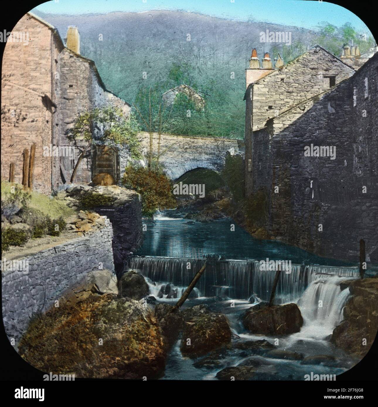 Farbige Skioptik mit Motiven von Gewölbebrücke und kleinerem Wasserfall in unbekannter mittelalterlicher Stadt. Stockfoto