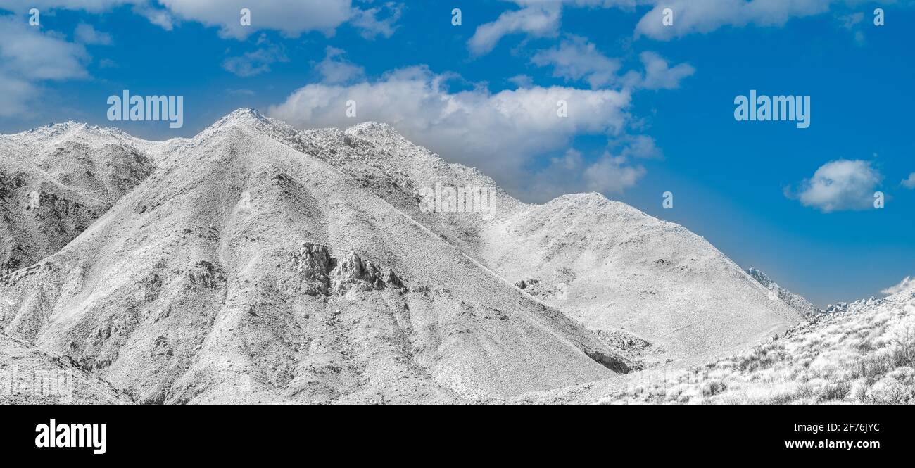 Schneebedeckter Berg unter blauem Himmel mit weißen, flauschigen Wolken. Stockfoto