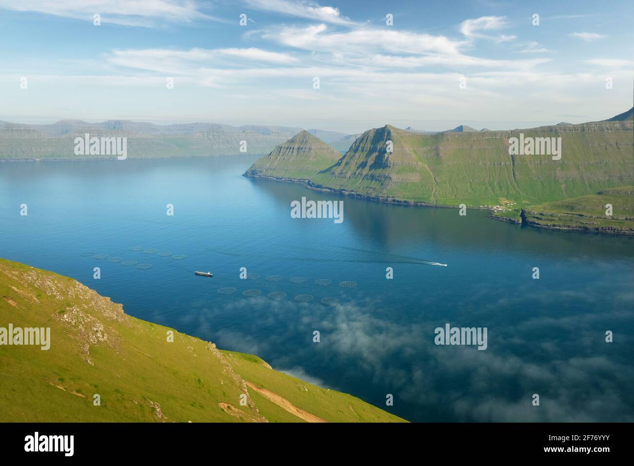 Fischfarm mit Schiff auf foggen Fjorden von Funningur, Insel Eysturoy, Färöer. Landschaftsfotografie Stockfoto
