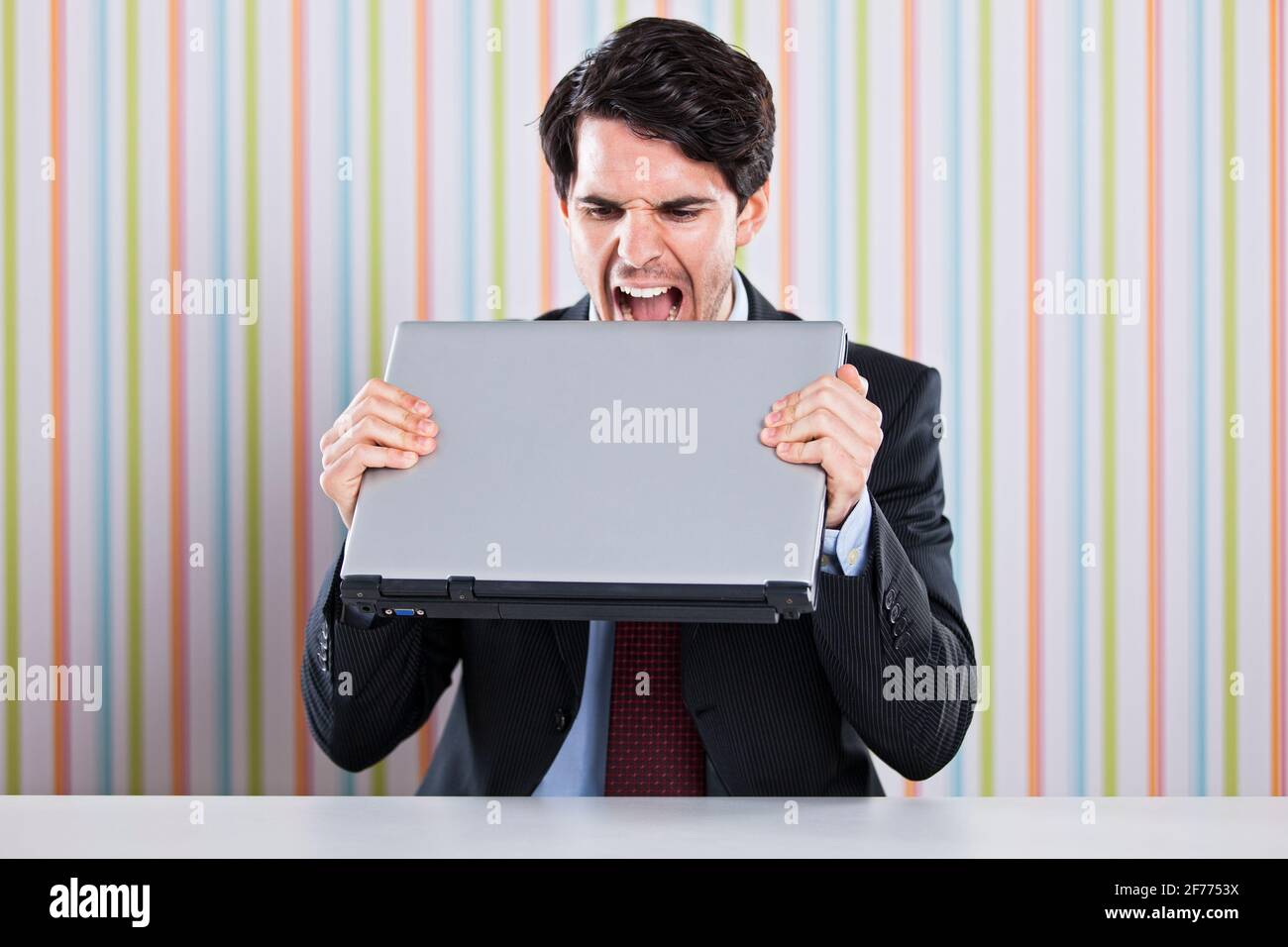 Verrückter Geschäftsmann, der seinen Laptop isst Stockfoto