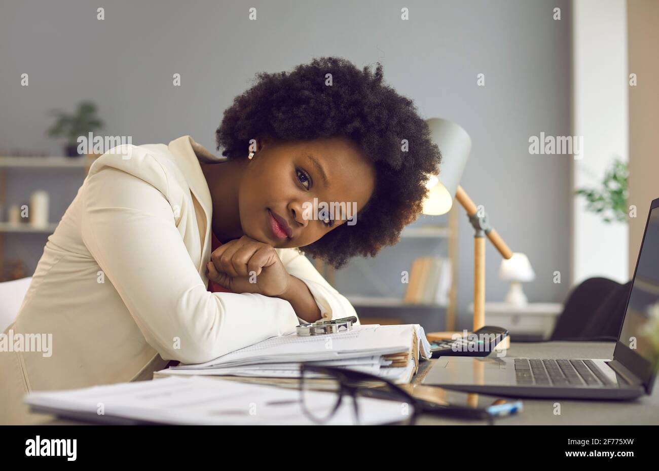 Porträt einer erfolgreichen jungen Geschäftsfrau, die am Schreibtisch sitzt und Blick auf die Kamera Stockfoto