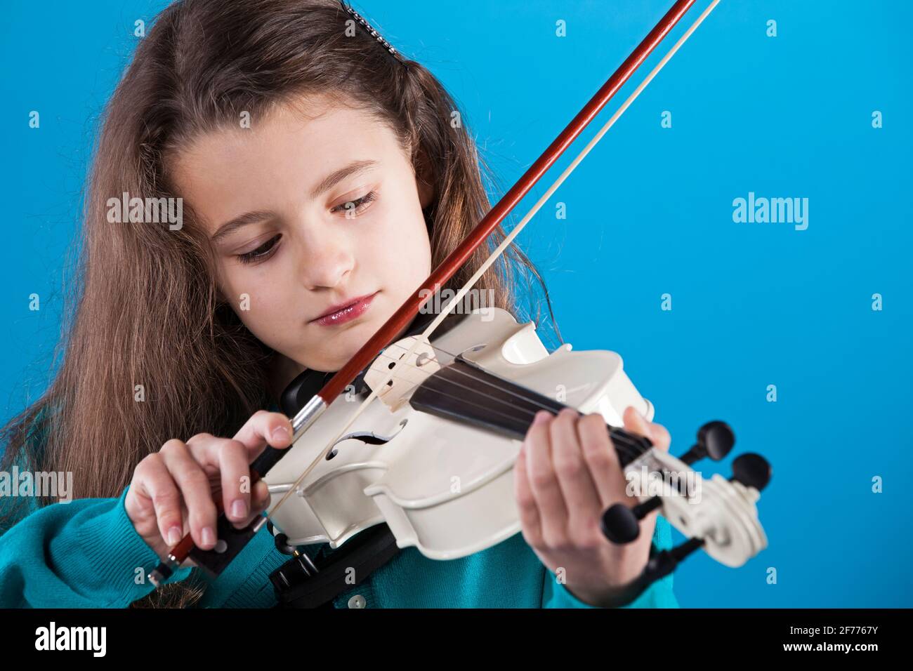 Mädchen spielt Geige mit blauem Hintergrund Stockfoto