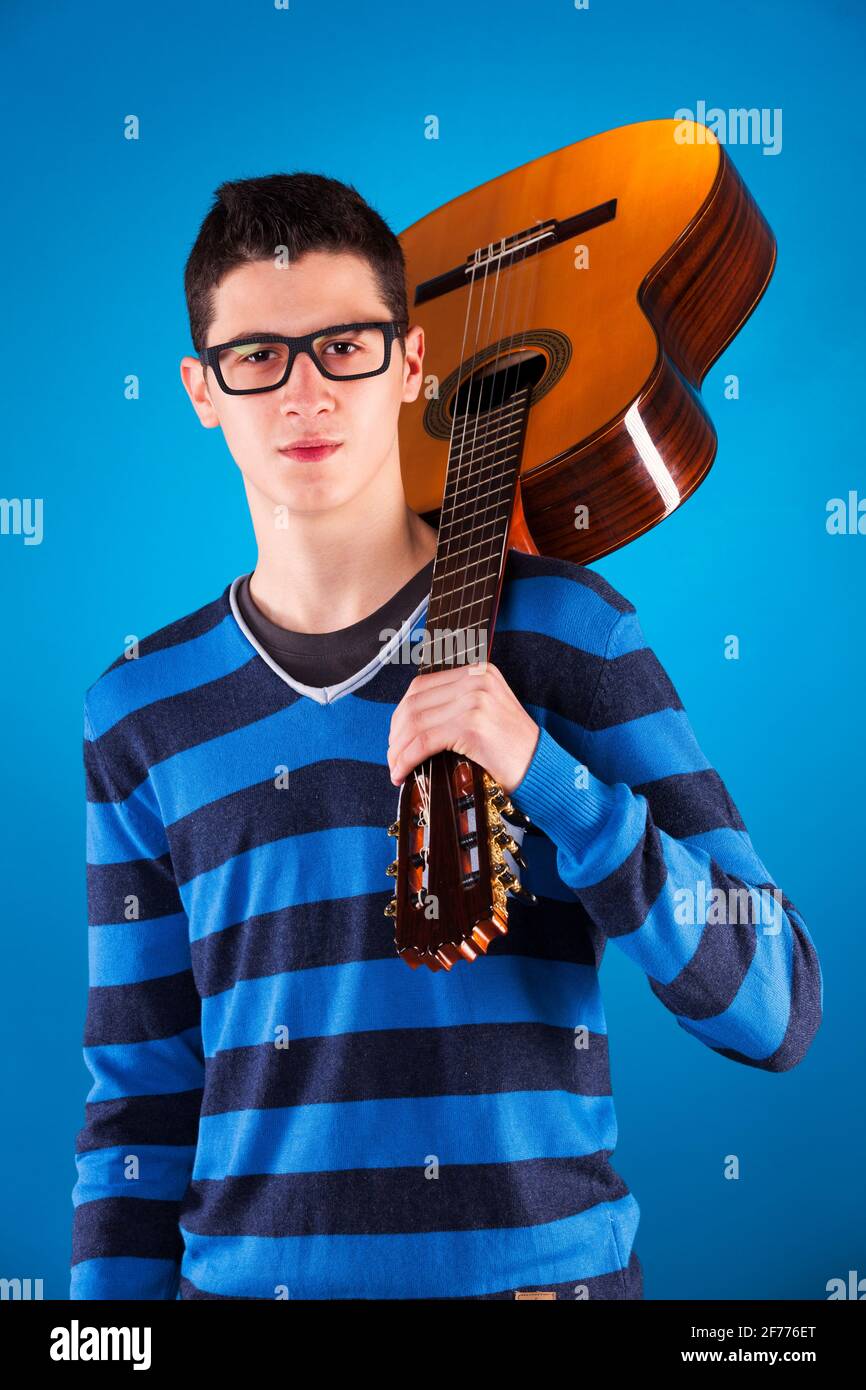 Teenager mit einer klassischen Gitarre mit blauem Hintergrund Stockfoto