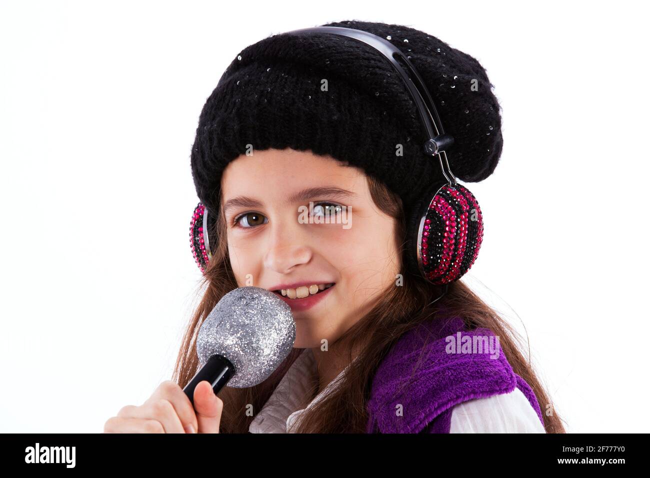 Weibliches Kind, das mit einem Mikrofon und Kopfhörern singt Stockfoto