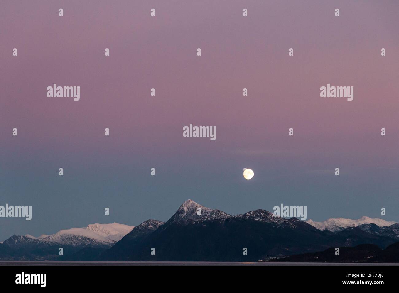 La Luna zeigt die bunte Pracht des Dämmerungshimmels, der von der alpinen Robustheit des nordwestlichen Fjordbezirks Norways untermauert wird Stockfoto