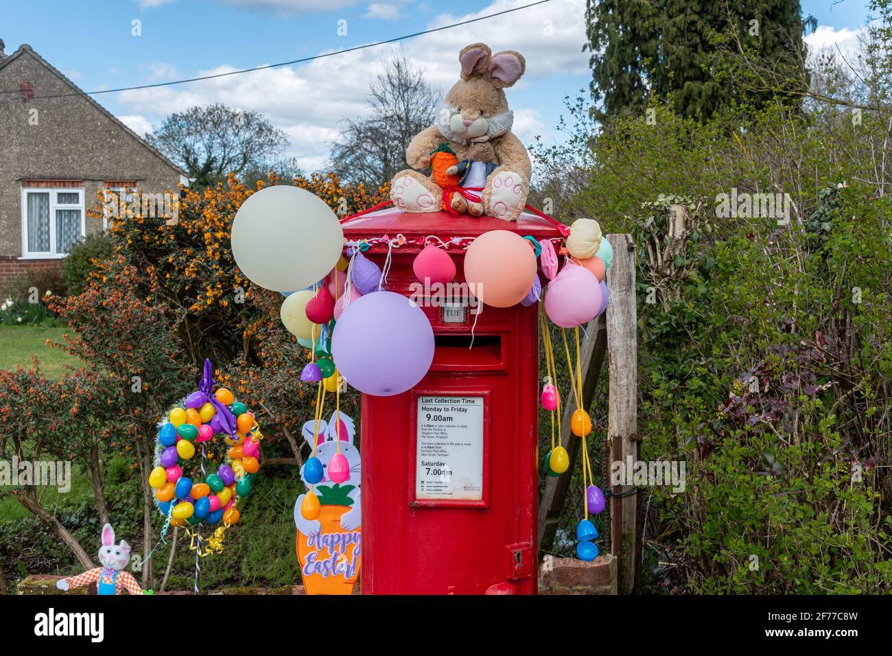 Osterschmuck mit Osterhasen und Ballons auf einem roten Briefkasten oder einer Briefbox, Großbritannien Stockfoto