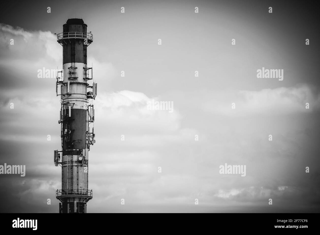 Rot-weißer Hochheizungskamin, der als Antennenmast mit Kopierraum, Schwarz-Weiß-Bild dient Stockfoto