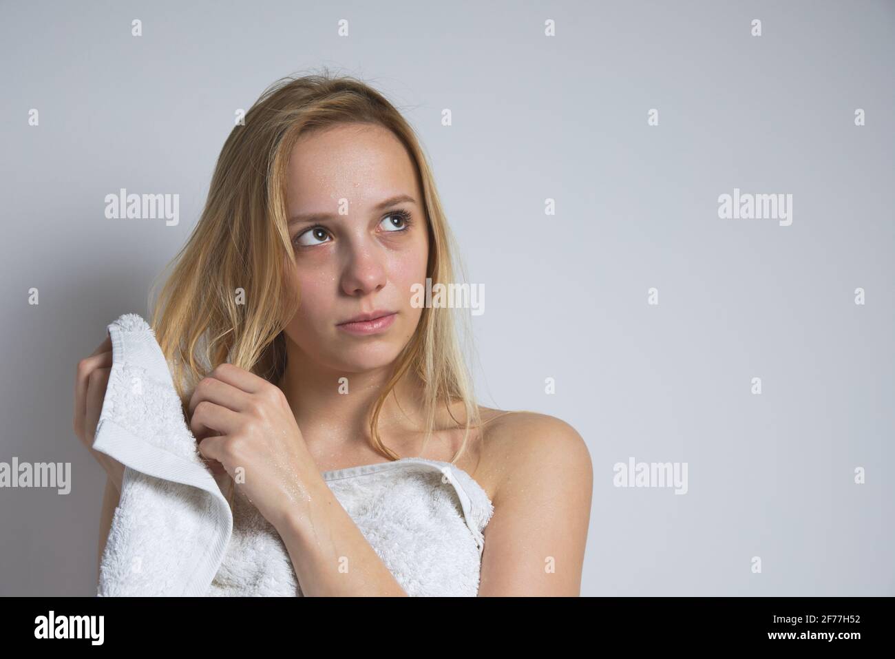 Junge schöne nasse Blonde kaukasische Frau wischt ihr Haar mit Weißes Handtuch Stockfoto