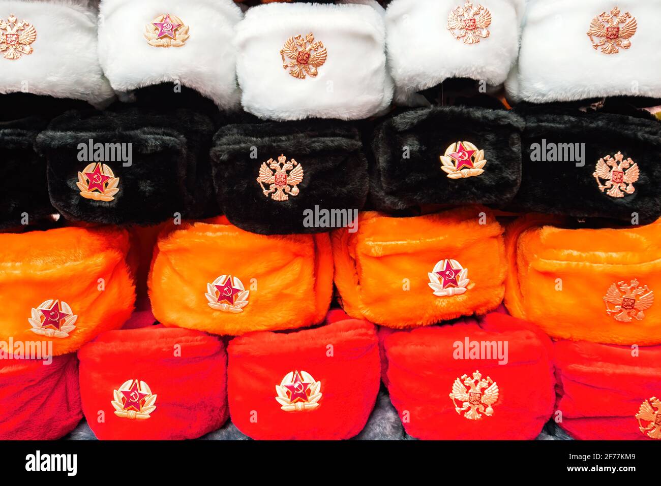 Moskau, Russland - 4. April 2021: Reihen von russischen Wintermützen in verschiedenen Farben mit Armeemblemen auf dem Straßenmarkt in der Old Arbat Street, ikonisches beliebtes Souvenir aus Russland. Hochwertige Fotos Stockfoto