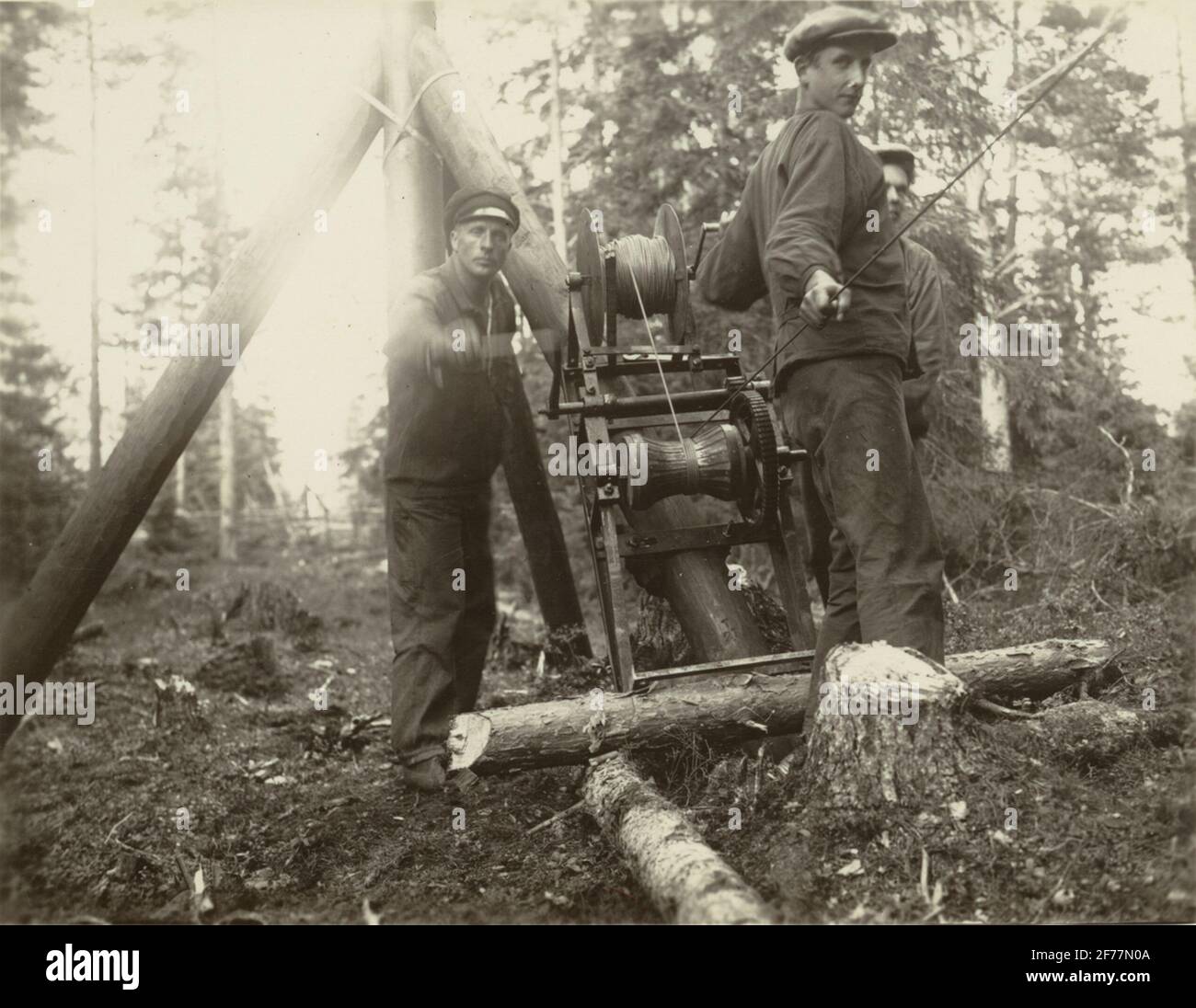 Drei Männer in der Arbeit.Helm atrid Kabel. Winde für Verdrahtung. Aus dem Album Kabelarbeit. Helmälra - Norrtälje - Finnviken trat im Sommer 1928 auf. Stockfoto