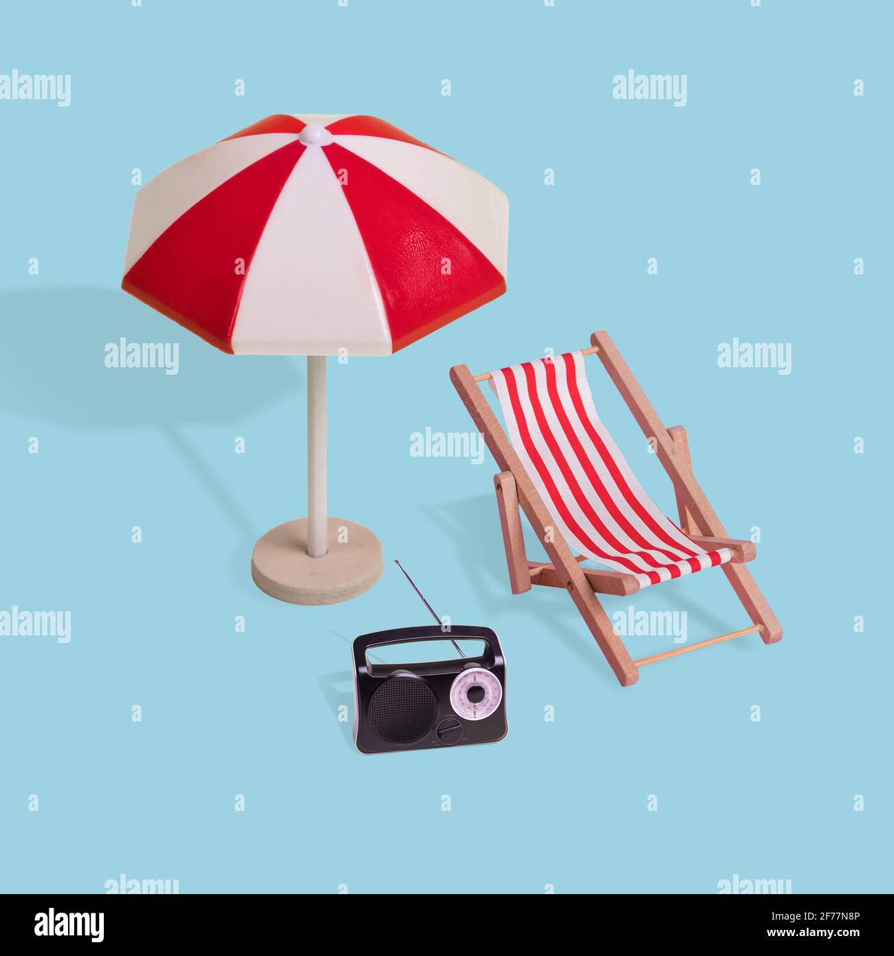 Kreative Minimal-Sommeridee aus Sonnenschirm, Liegestuhl und Radio auf pastellblauem Hintergrund. Modernes Konzept von Urlaub, Reisen, Spaß und Summ Stockfoto