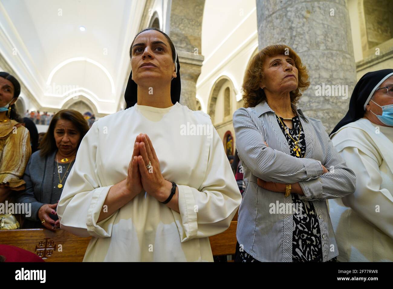 Mosul, Ninive, Irak. April 2021. Irakische Christen nehmen an der Ostermesse in der Großen Unbefleckten Kirche (al-Tahira-l-Kubra) in der Stadt Qaraqosh (Al-Hamdaniya), 30 Kilometer südöstlich der Stadt Mosul, Teil. Ostern gilt als größter und größter christlicher Feiertag, Es erinnert an die Auferstehung Christi von den Toten nach drei Tagen seiner Kreuzigung und seines Todes, wie im Neuen Testament geschrieben, in dem die große Fastenzeit, die gewöhnlich vierzig Tage dauert, endet. Während der Liturgie werden die Hymnen gesungen, Teile des Alten Testaments aus der Bibel rezitiert, die Hymnen des Hallelujah ar Stockfoto