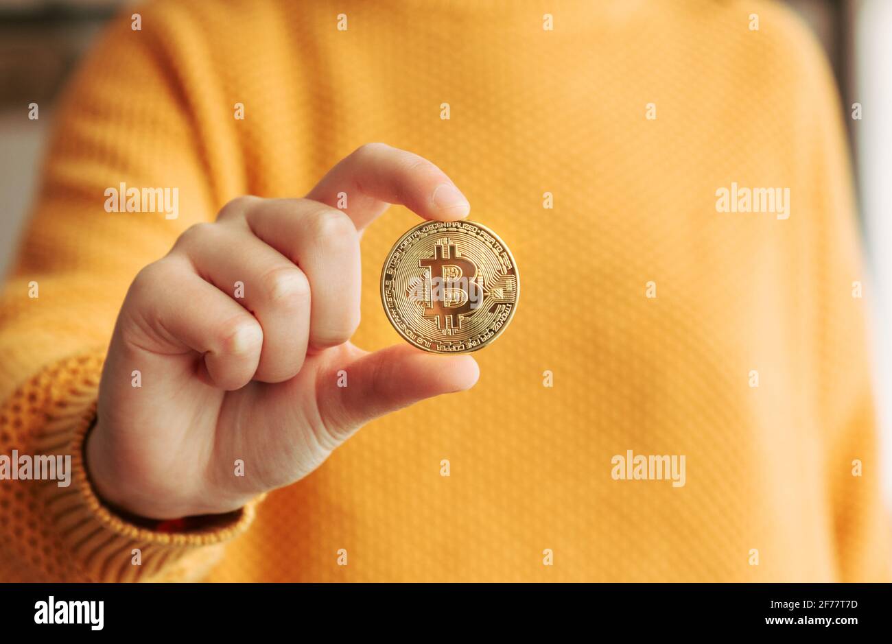 Frau mit einer goldenen Bitcoin in der Hand. BTC und Kryptowährungen in einem digitalen dezentralen Finanzkonzept Stockfoto
