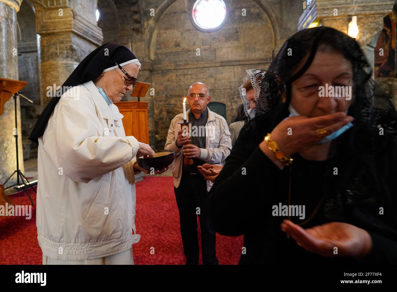 Mosul, Ninive, Irak. April 2021. Irakische Christen erhalten während der Ostermesse in der Großen Unbefleckten Kirche (al-Tahira-l-Kubra) in der Stadt Qaraqosh (Al-Hamdaniya), 30 Kilometer südöstlich der Stadt Mosul, die heilige Kommunion. Es erinnert an die Auferstehung Christi von den Toten nach drei Tagen seiner Kreuzigung und seines Todes, wie im Neuen Testament geschrieben, in dem die große Fastenzeit, die gewöhnlich vierzig Tage dauert, endet. Während der Liturgie werden die Hymnen gesungen, Teile des Alten Testaments aus der Bibel rezitiert, das Hymn Stockfoto