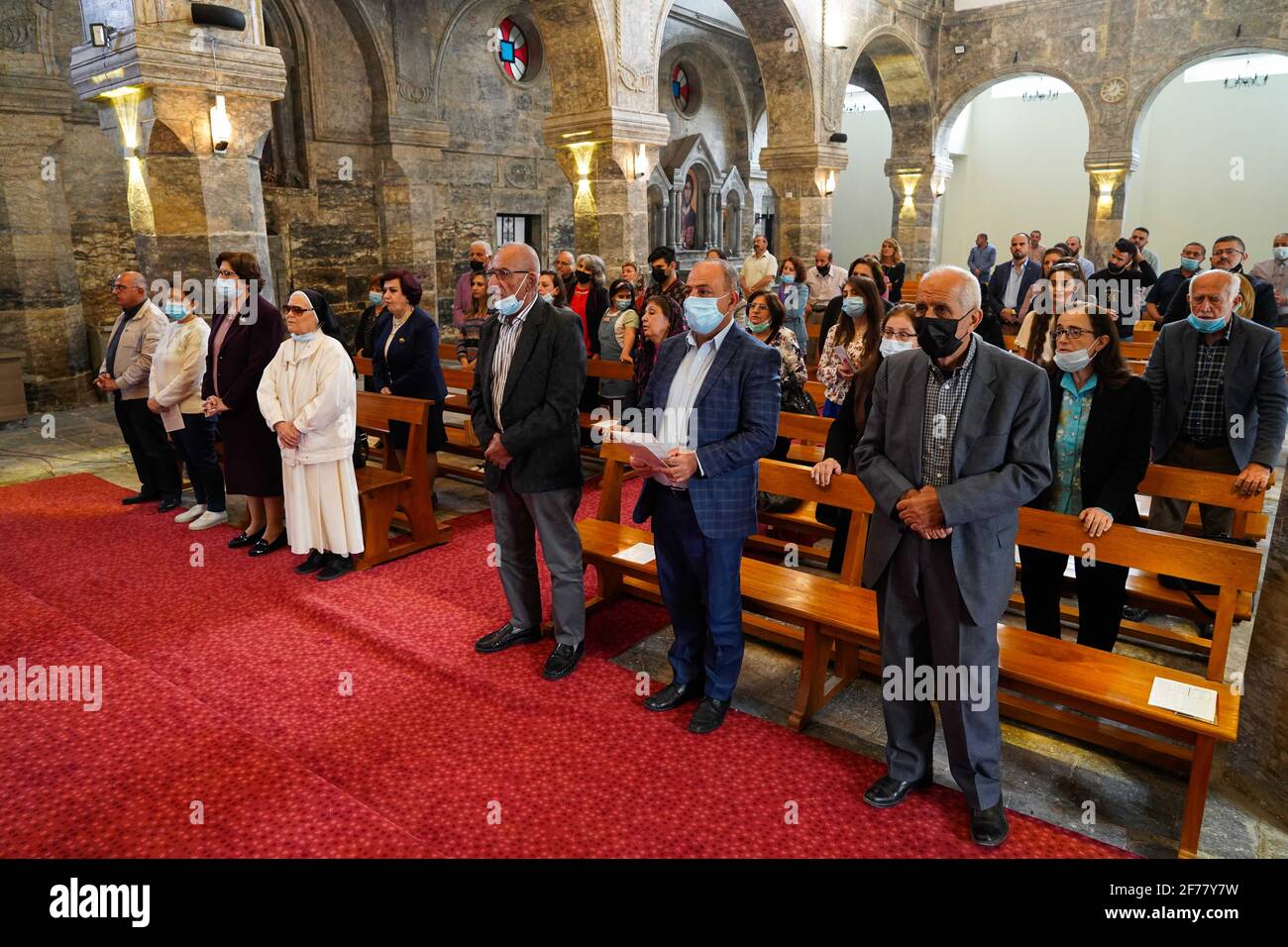 Mosul, Ninive, Irak. April 2021. Irakische Christen nehmen an der Ostermesse in der Großen Unbefleckten Kirche (al-Tahira-l-Kubra) in der Stadt Qaraqosh (Al-Hamdaniya), 30 Kilometer südöstlich der Stadt Mosul, Teil. Ostern gilt als größter und größter christlicher Feiertag, Es erinnert an die Auferstehung Christi von den Toten nach drei Tagen seiner Kreuzigung und seines Todes, wie im Neuen Testament geschrieben, in dem die große Fastenzeit, die gewöhnlich vierzig Tage dauert, endet. Während der Liturgie werden die Hymnen gesungen, Teile des Alten Testaments aus der Bibel rezitiert, die Hymnen des Hallelujah ar Stockfoto