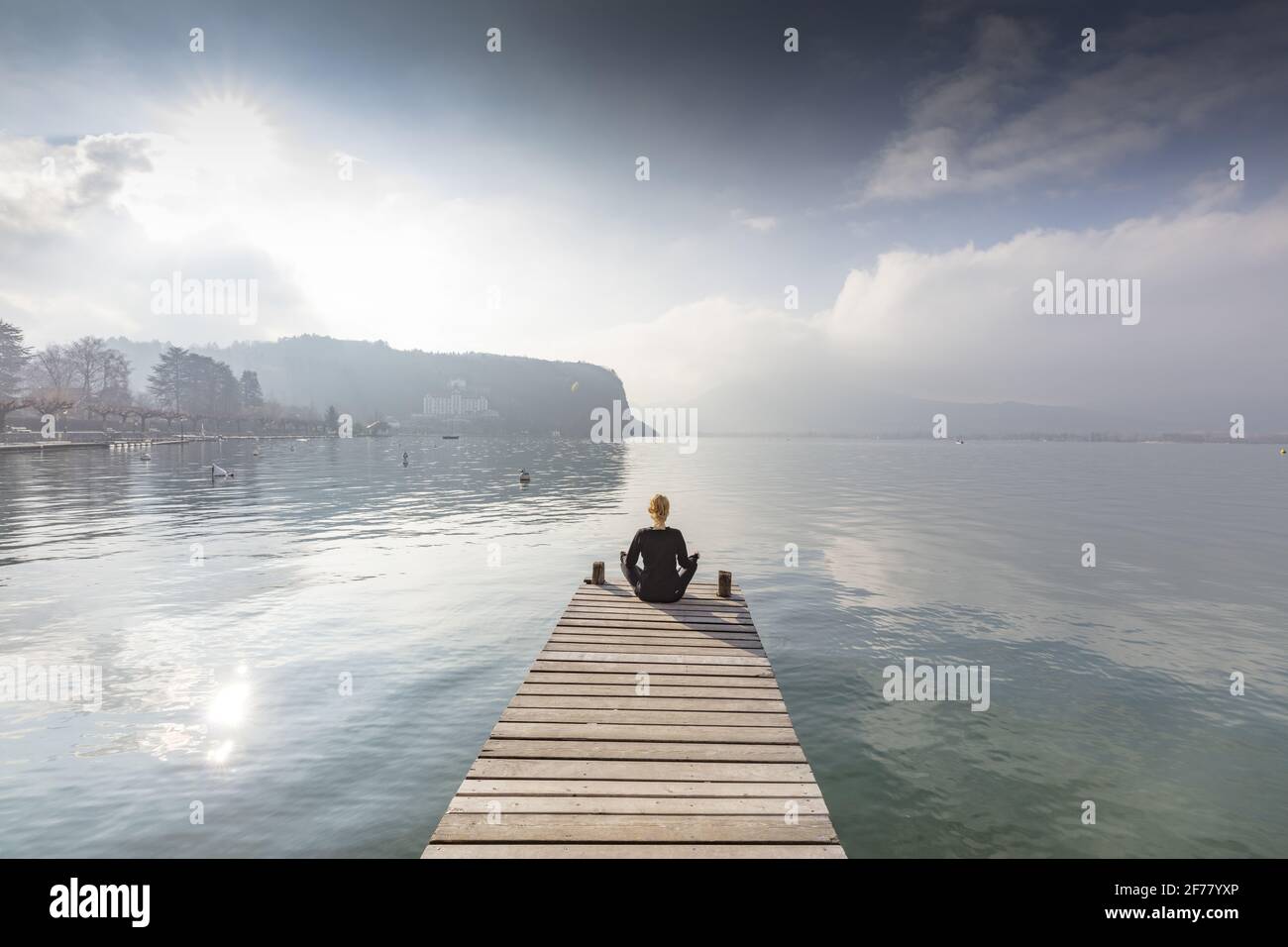 Frankreich, Haute Savoie, Annecy, See Annecy, vor dem Palast von Menthon, junge Frau auf einem Ponton in Meditation mit Blick auf den See Stockfoto