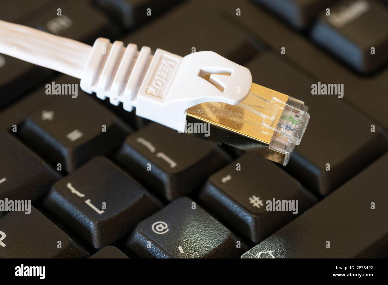 Nahaufnahme eines weißen ethernet-Kabels (Internet) auf einer schwarzen Tastatur. Konzept: internetzugang, Breitband, Internetausfall, Hacking, digital Stockfoto