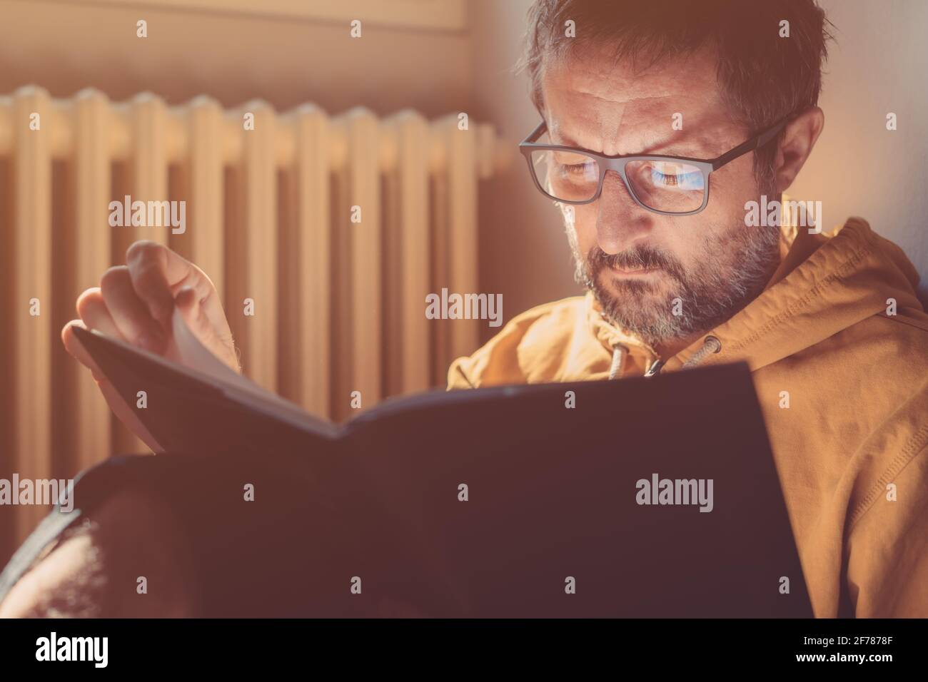 Bibliophiler Mann mit mittlerem Erwachsenen, der zu Hause ein Buch liest, Nahaufnahme-Kopfbild mit selektivem Fokus Stockfoto