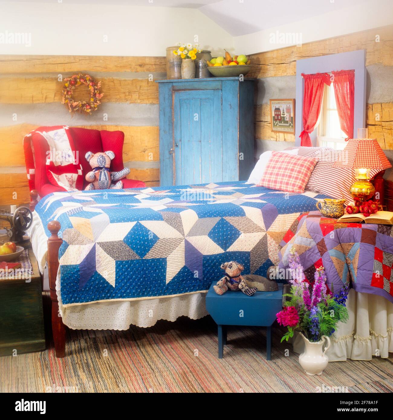 90ER JAHRE BLOCKHÜTTE SCHLAFZIMMER INNENAUSSTATTUNG RUSTIKALE MÖBEL TRADITIONELLE BUNTE BAUMWOLLE STEPPDECKE UND KISSEN AUF DEM BETT, VASE MIT BLUMEN AUF DEM BODEN