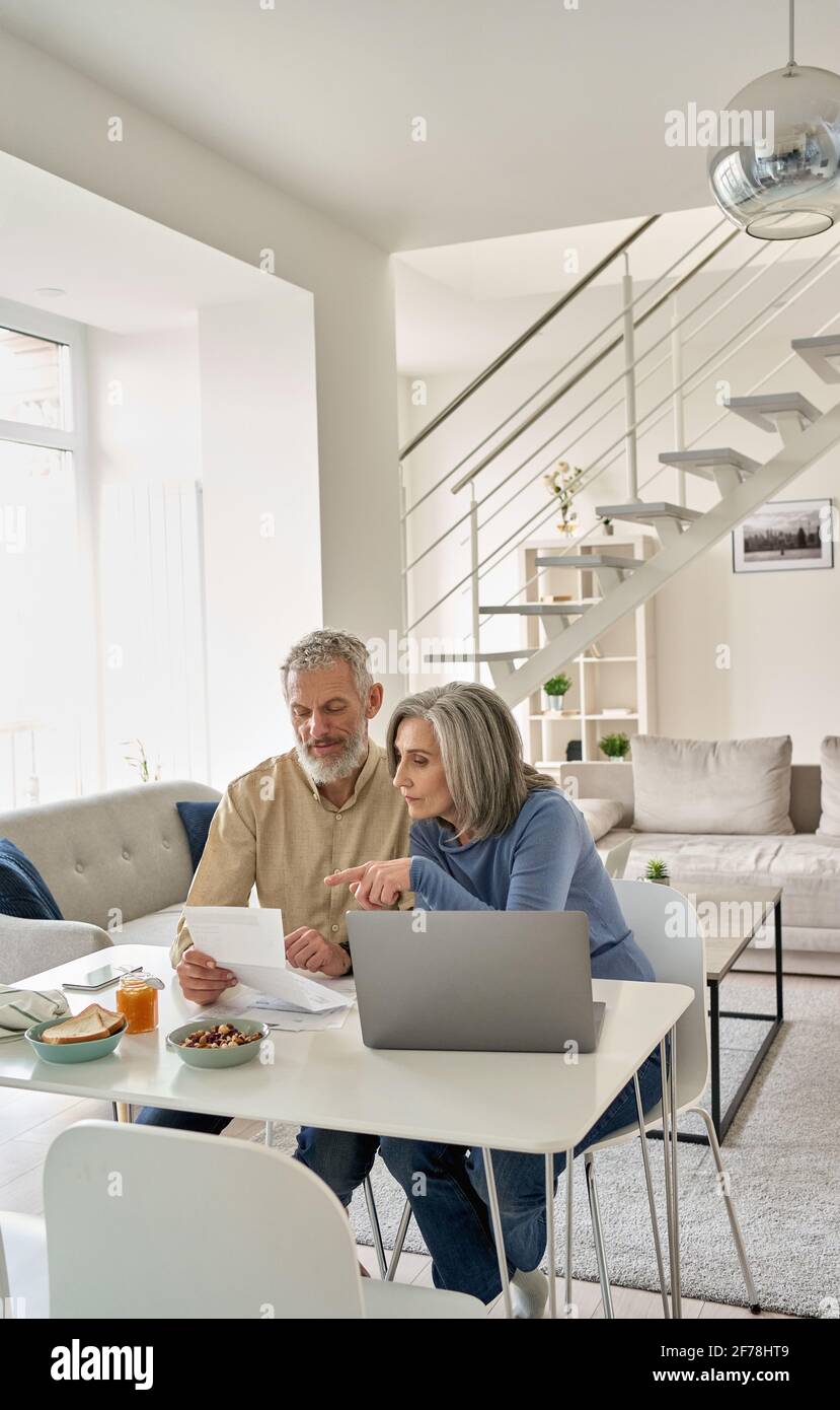 Ältere Paare, die zu Hause Bankdokumente mit einem Laptop überprüfen. Stockfoto