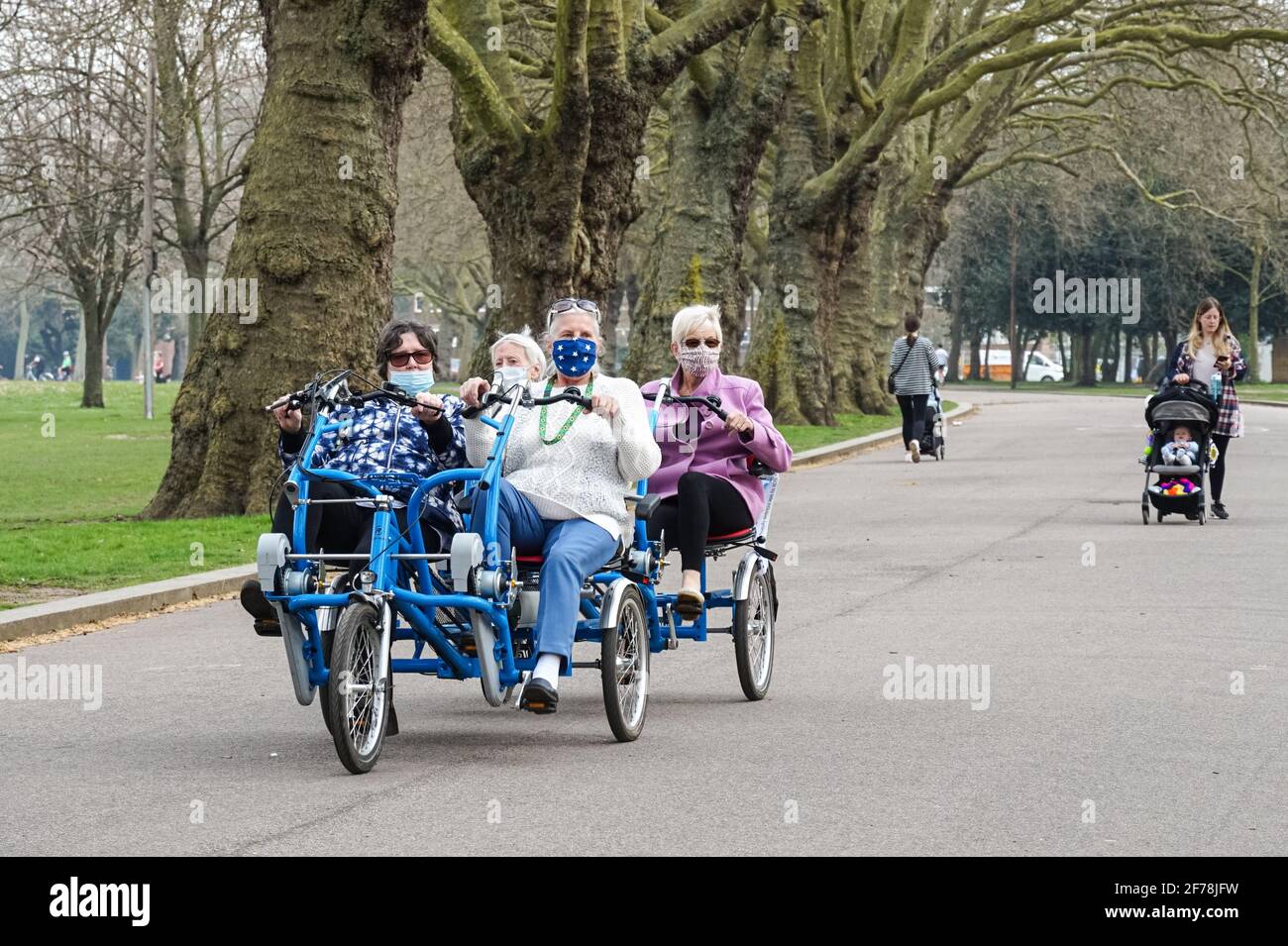 Ältere Frauen tragen Gesichtsmasken und reiten auf einem Vierrad in einem Park während der Coronavirus-Epidemie in London, England, Großbritannien Stockfoto