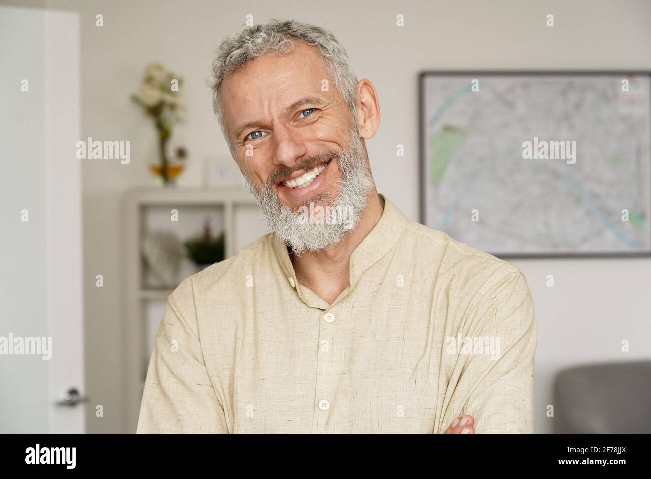 Lächelnder, reifer bärtiger Mann, der zu Hause auf die Kamera schaut, ein Kopfbildnis. Stockfoto