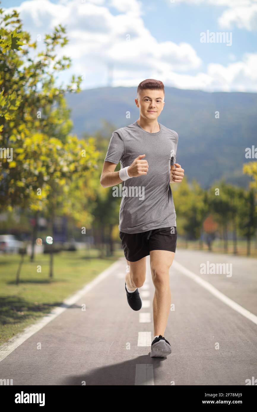 Ganzkörperportrait eines Mannes, der auf einem Asphalt joggt Fahrspur Stockfoto