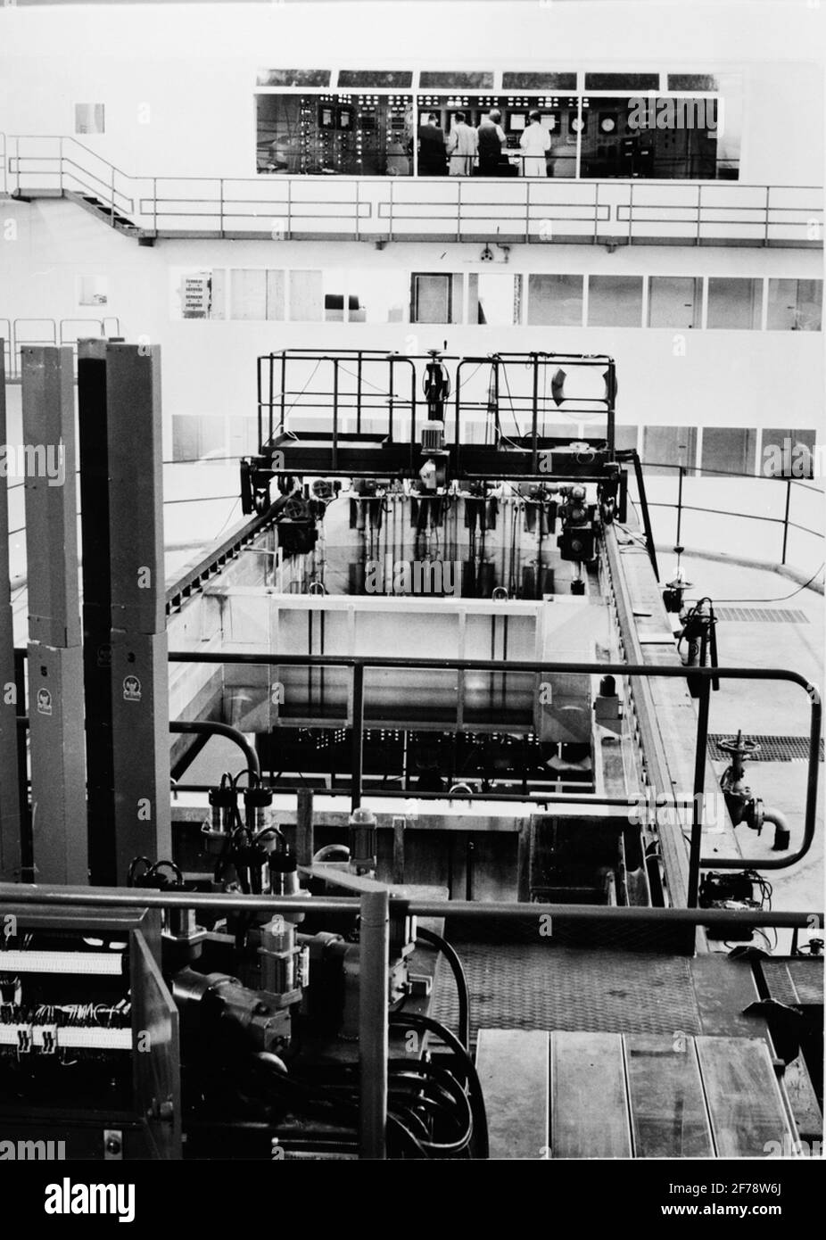 Der R2-Reaktor in der Studsvik.Bassängen und dem Kontrollraum. Das 9 Meter tiefe Becken, das mit Wasser gefüllt ist, ist in drei Abteilungen unterteilt. Der mittlere Teil wird zur Lagerung bestimmter Bestände verwendet. In der Abteilung, die der Kamera am nächsten liegt, wurde der R2-0-Reaktor aufgestellt. Stockfoto