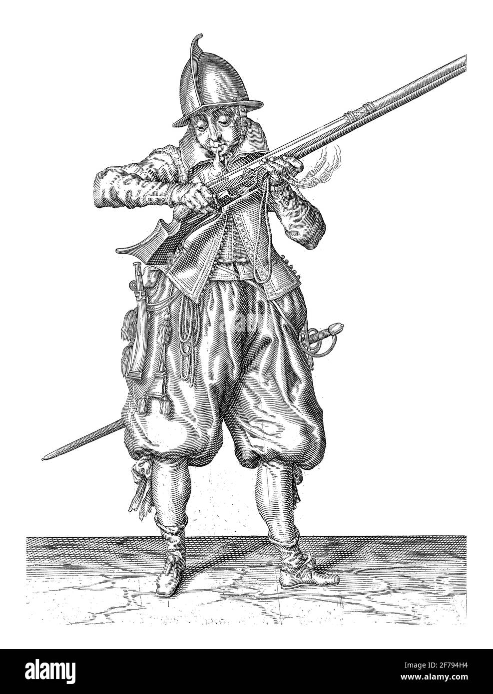 Ein Soldat in voller Länge hält mit beiden Händen ein Ruder (eine bestimmte Art von Feuerwaffe) an seinen Mund und bläst es darüber, um jedes Pulver zu bekommen, das angeschlagen ist Stockfoto