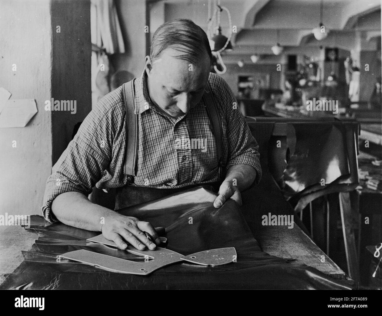 Der Schneider untersucht jeden Teil der Haut, um Materialfehler im oberen Leder zu vermeiden. Stockfoto