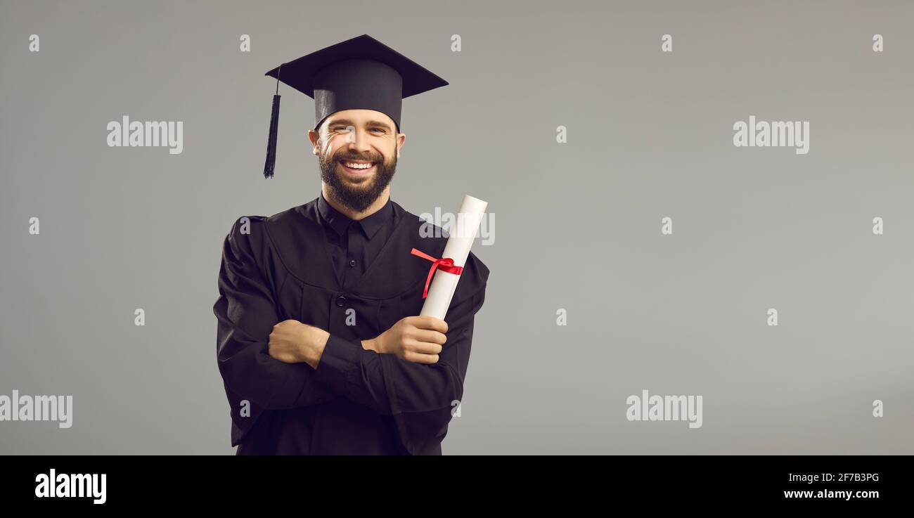 Porträt eines glücklichen Studenten in einem akademischen Kleid und Hut mit einer Universität oder Akademie Zertifikat. Stockfoto