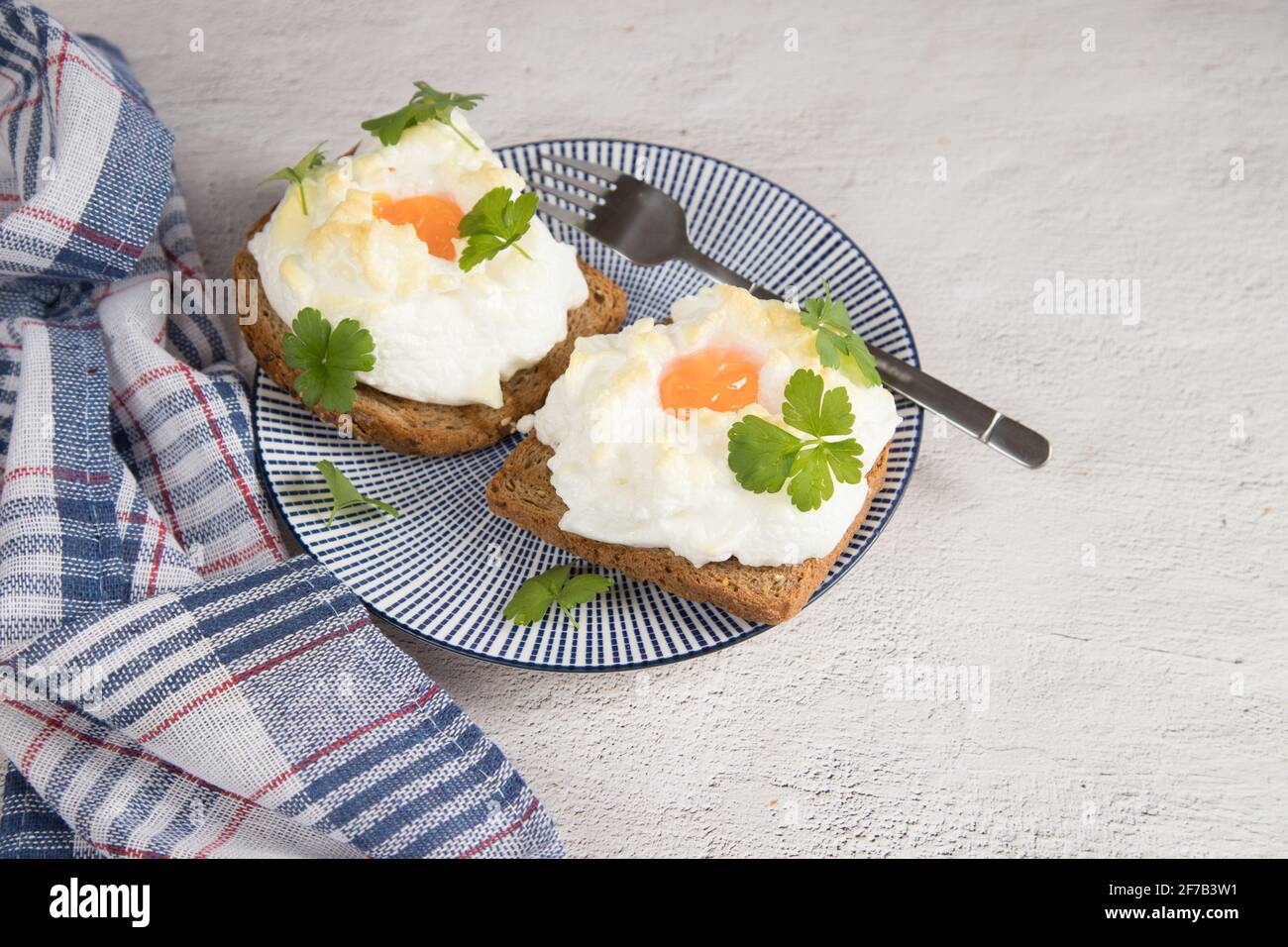 Auf einem hellen Hintergrund ein Teller mit einem Diät-Frühstück mit gebackenem Toast mit geschlagenen Eiern. Stockfoto
