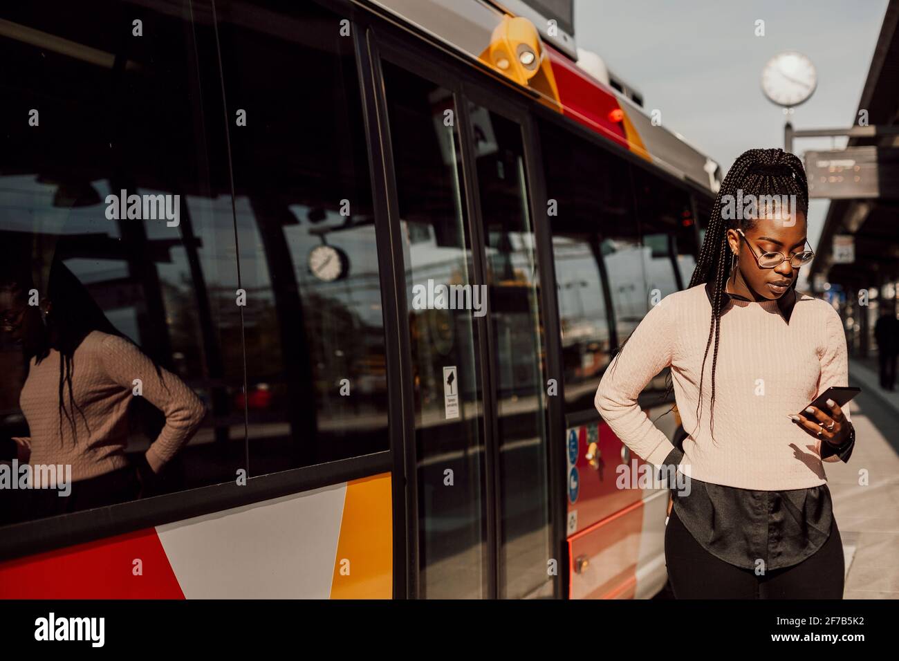 Junge Frau warten am Busbahnhof Stockfoto